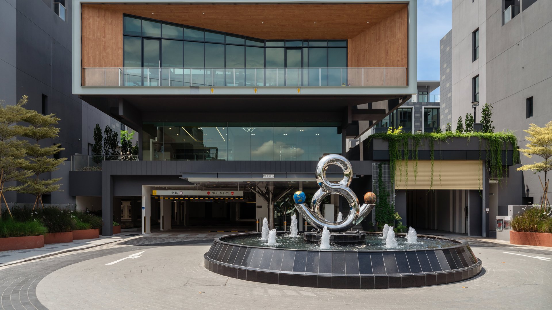 Two-storey clubhouse with timber-clad upper level and roundabout sculpture fountain at the Belgravia Ace grand drop-off