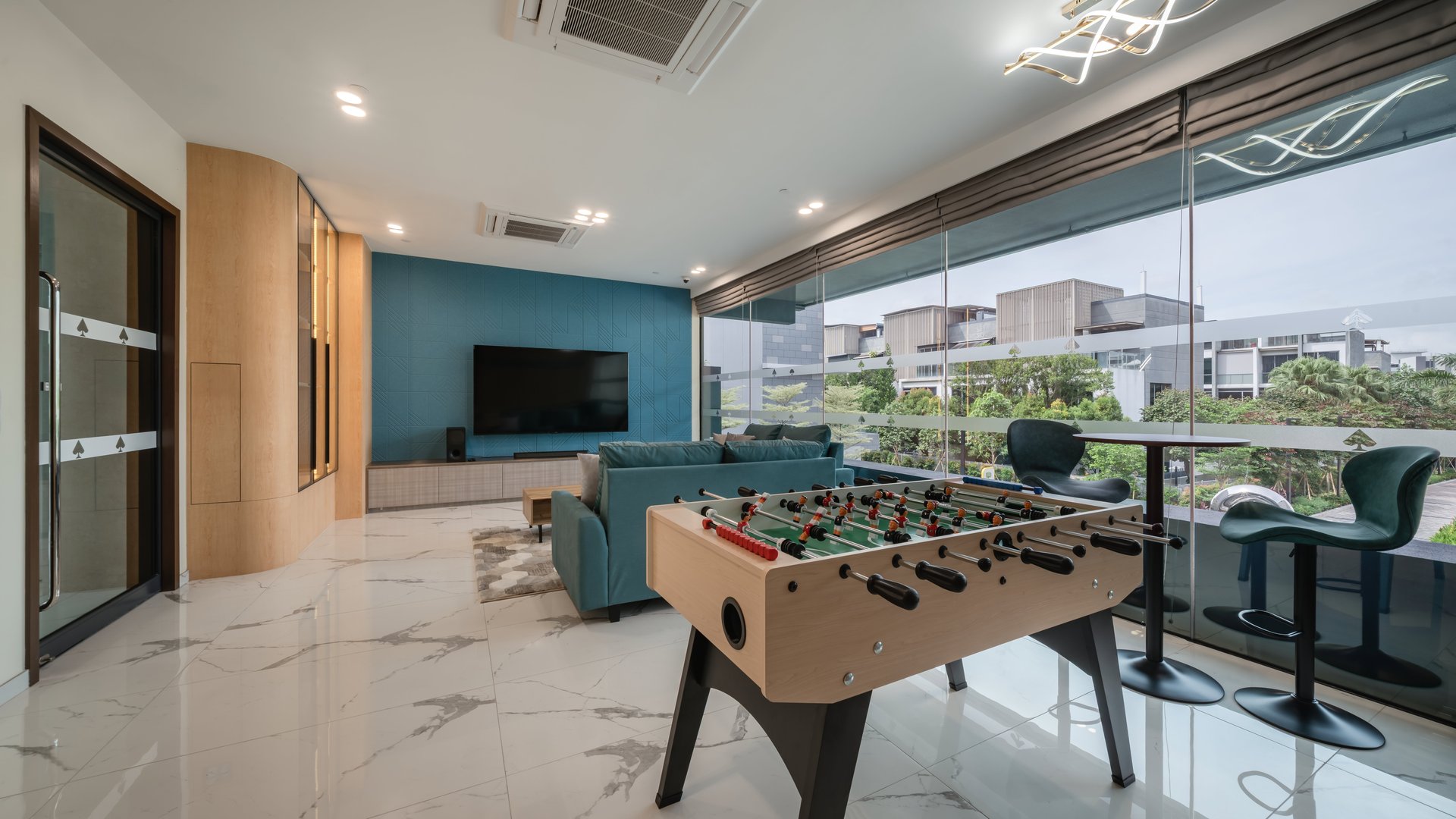 Clubhouse games room with foosball table, sofa, TV and glass wall overlooking the estate at Belgravia Ace