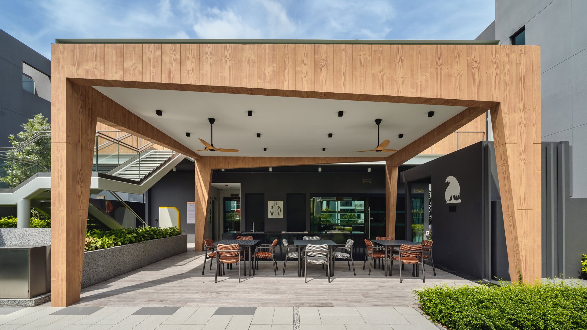 Covered timber-clad pavilion with dining tables and ceiling fans at Belgravia Ace clubhouse