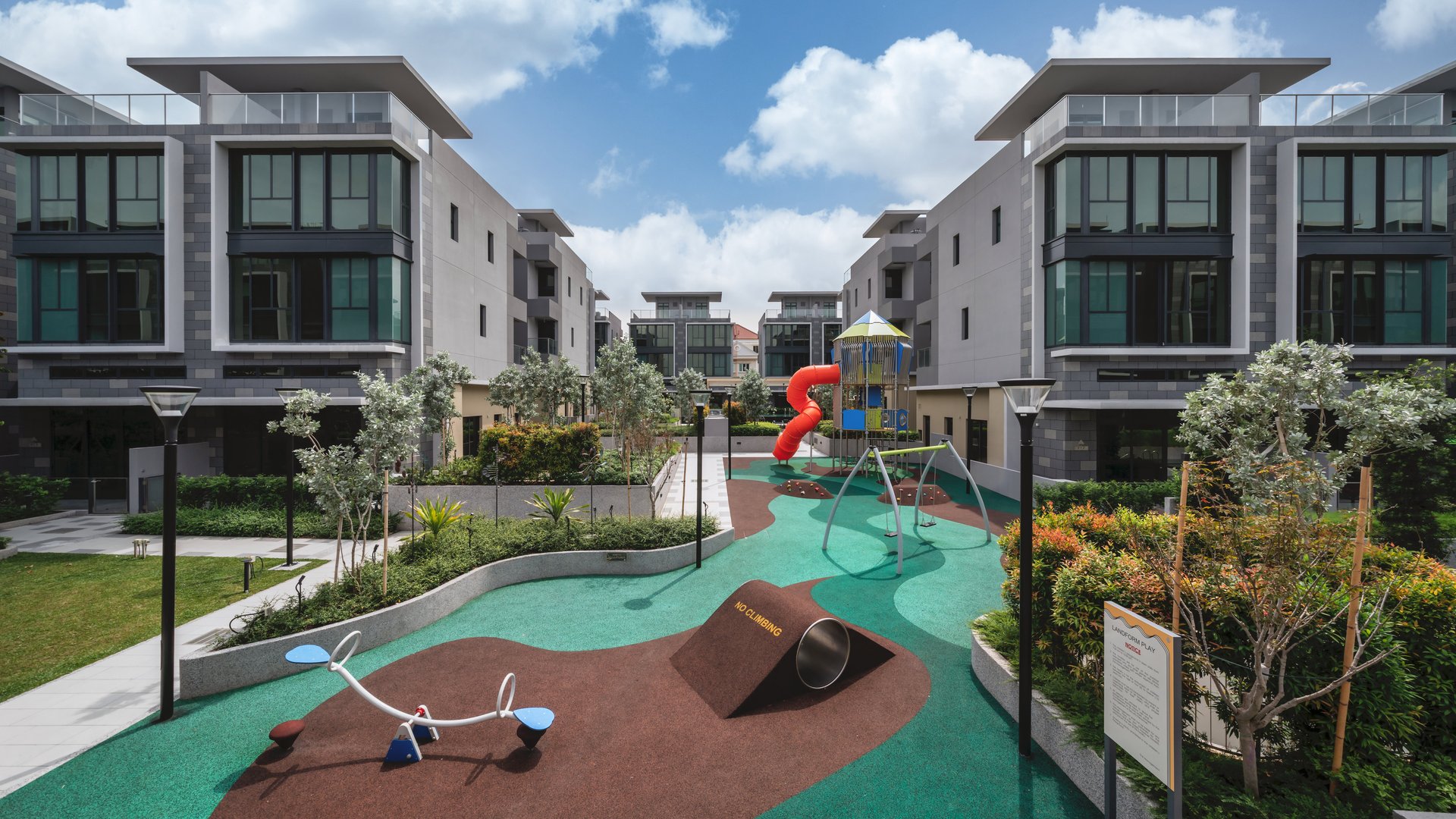 Children's playground with spiral slide, swings and play mounds between houses at Belgravia Ace
