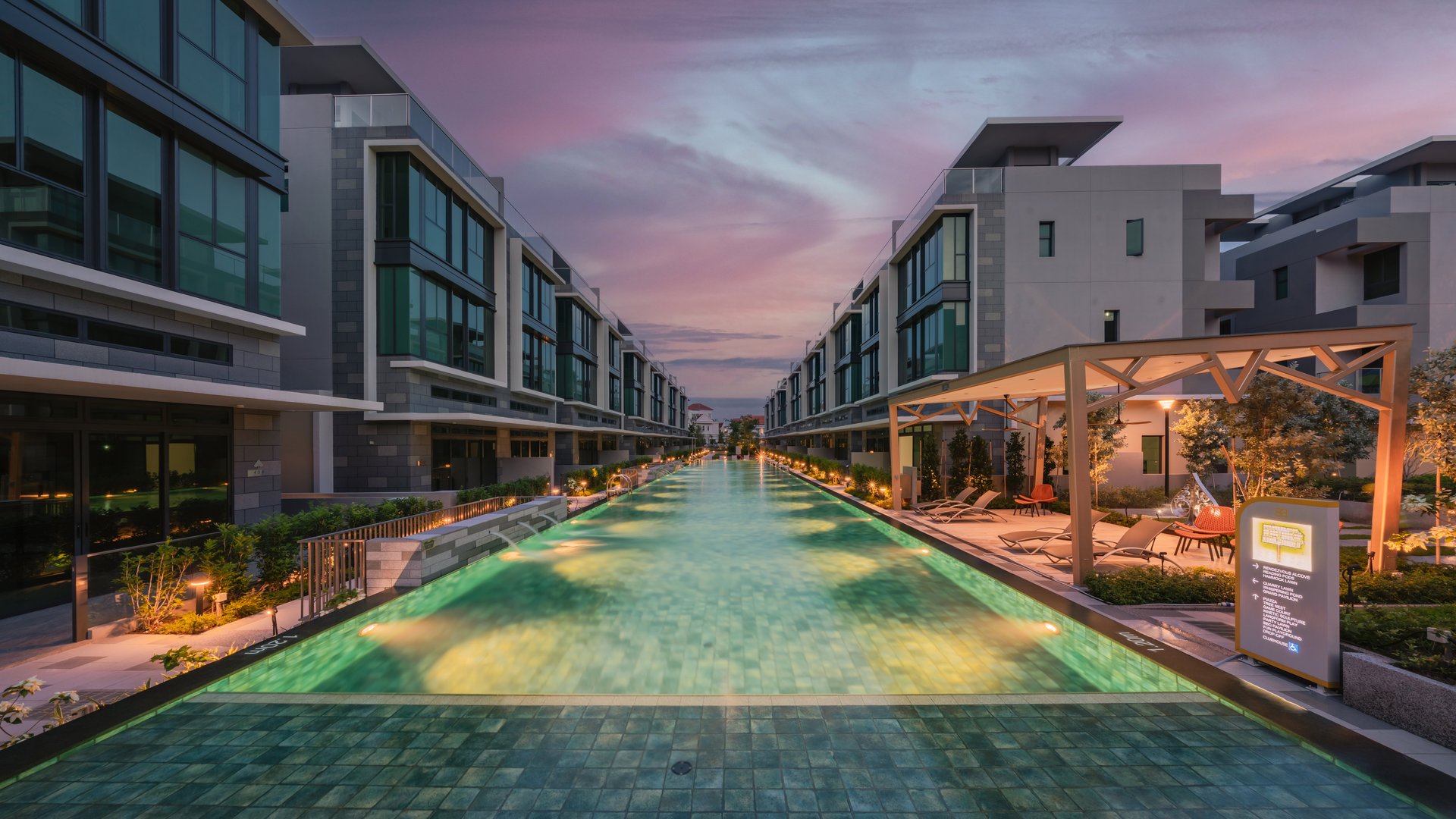 50 m lap pool lit at dusk between rows of strata semi-detached houses at Belgravia Ace, District 28